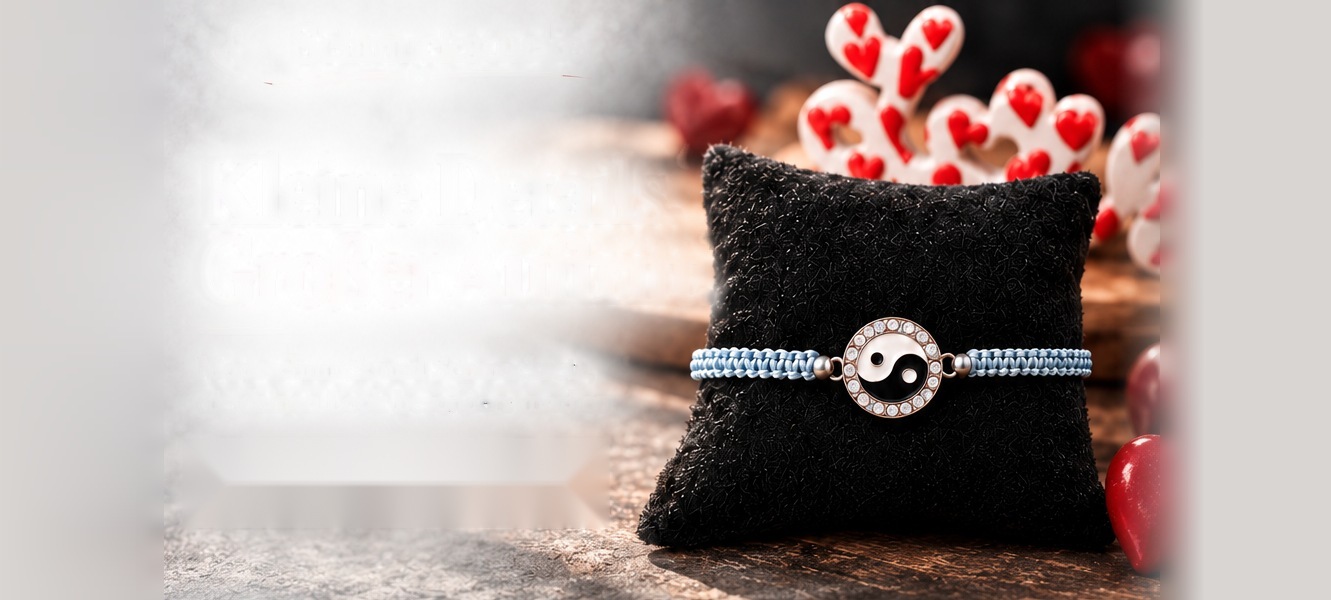 Makramee-Armband mit Yin-Yang-Anhänger auf schwarzem Kissen, dahinter rote Herzen